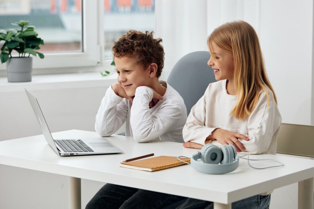Happy children studying at home with laptops, headphones, and tablets Both a boy and a girl are